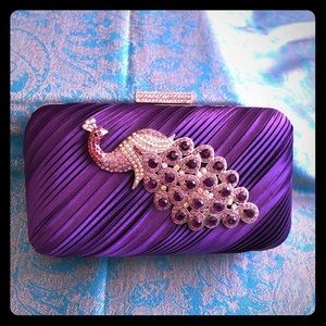 Purple purse with rhinestone peacock detail.